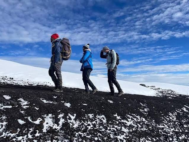 Trekkers approaching the jagged volcanic spires of Mawenzi Tarn camp